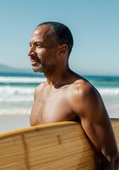 Middle-aged African American man holding surfboard at sunny beach