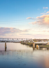 Fototapeta premium Bridge spans a river with a beautiful sunset in the background