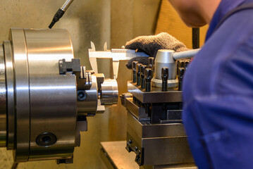 Close up scene the machine operator measuring dimension of turning parts by Vernier caliper.