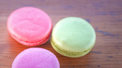 Three macarons of different colors are sitting on a wooden table