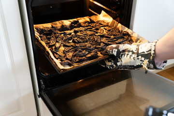 Man taking burnt potaoes out of oven.