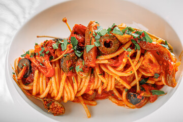 Portion of gourmet spaghetti pasta with tomato sauce and olives