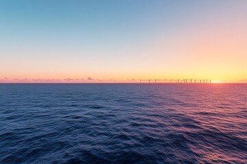 Obraz premium Aerial view captures an offshore wind farm featuring a row of turbines against a serene blue ocean. Soft orange hues from the sunset enhance the tranquil scene