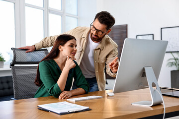 Colleagues working with computer at desk in office