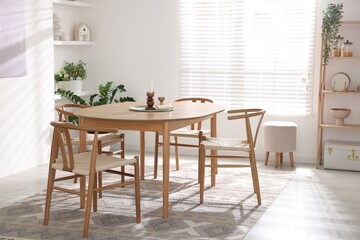 Stylish room with wooden table, chairs and houseplants. Interior design