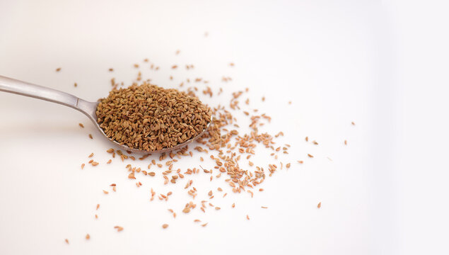 Ajwain seeds in a spoon over white background. Selective focus.