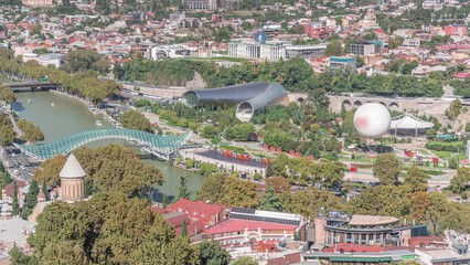 Aerial timelapse of Rike Park, a modern urban park in Tbilisi's Old Town with green trees and lawns. The Bridge of Peace in the background. Georgia © HyperlapsePro