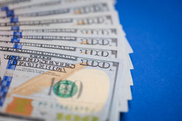 Close-up view of stacked u.s. one hundred dollar bills on blue background