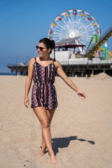 Young female tourist strolling along the beach by the pier in Santa Monica, California.