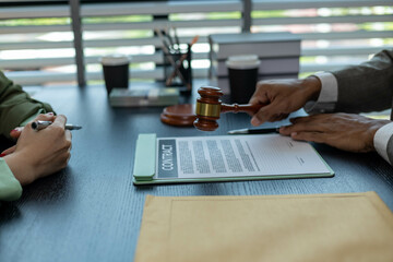 Fototapeta premium A man and a woman are sitting at a table with a judge. The man is handing the woman a piece of paper 