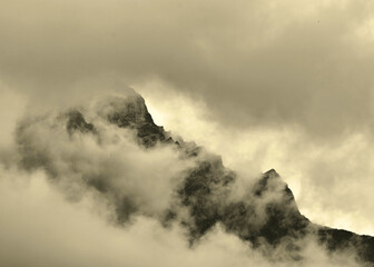 Storm clouds gathering around peak of rugged mountain range creating moody almost eire image.