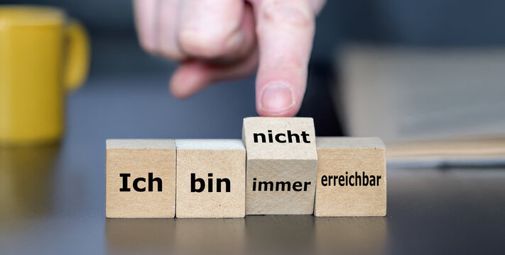 Hand turns a cube and changes the German expression 'ich bin immer erreichbar' (always available) to 'ich bin nicht erreichbar' (not available).