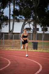 Female athlete in black sportswear training on a professional running track and running through various dynamic exercises, showcasing endurance, strength, and athleticism.