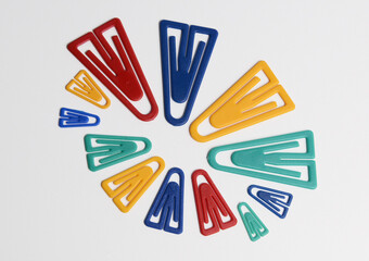 Plastic paper clips in various colors and sizes, isolated on white.