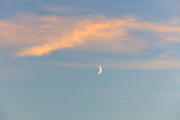 Crescent moon in tranquil sunset sky with soft clouds