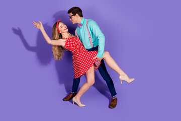 Elegant young couple posing stylishly against a violet backdrop, showcasing retro and fashionable...