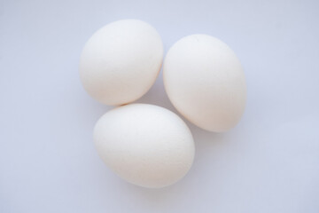 three white chicken eggs on a white background