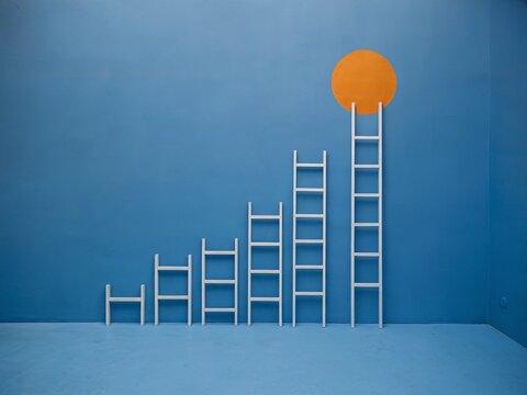A conceptual image showing several ladders arranged in increasing height symbolizing growth and progress.