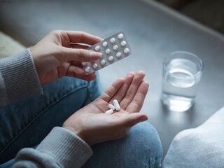 Person Holding Medication Pills With Glass of Water Nearby