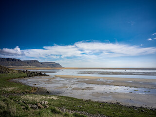 Plage sauvage &agrave; mar&eacute;e basse en Islande sous un ciel bleu &eacute;clatant
