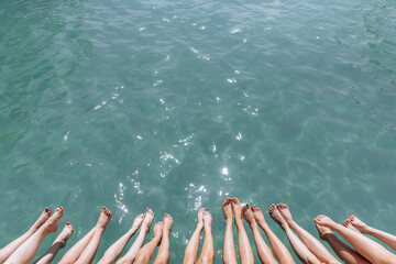 Photo from above of many girls' legs above blue sea water. Spa and swimming pool as entertainment for girls