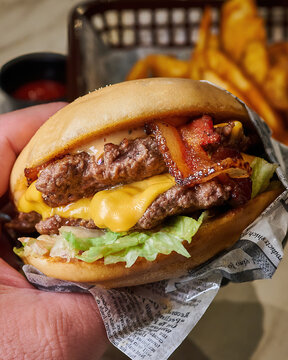 Handheld Double Cheeseburger with Crispy Bacon and Fries
