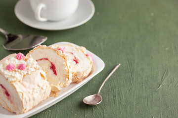 Homemade Meringue Cake Sweets Roll with Raspberry jam on ceramic plate.