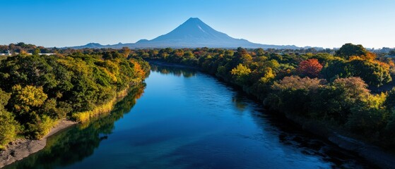 River flowing through valley with mountain peak in the background during sunny day with blue sky