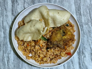Fried rice, vegetables, crackers and fried chicken. Fried rice on a plastic plate.	