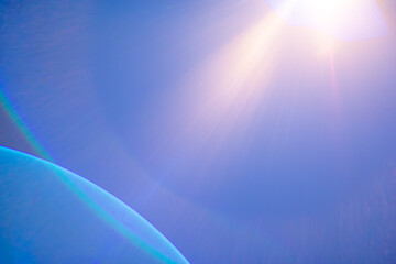 Bright lens flare enhances the vibrant blue sky with hints of celestial curvature.