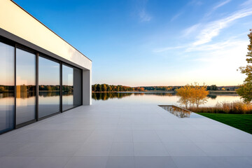 A modern lakeside view featuring a sleek structure, reflective water, and a serene landscape under a clear blue sky.