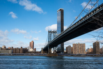 A bridge spans a river in a city with a clear blue sky