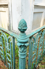 Cast iron ornate fence with artichoke ornament painted green.