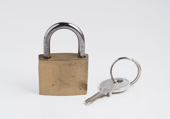 Small old solid brass padlock in close position with the key, isolated on white. 