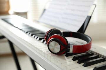 Synthesizer with music sheets and headphones indoors, closeup