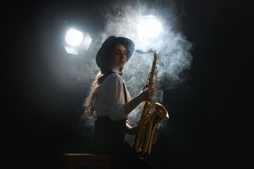 Professional musician playing saxophone on dark background with lights and smoke