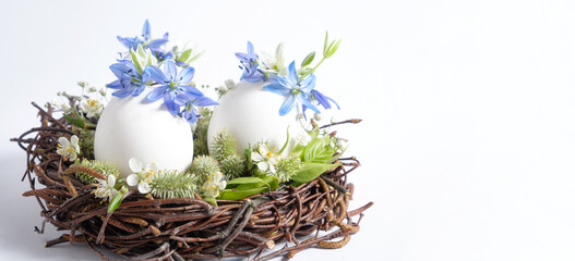 Original Easter decor with your own hands: easter nest with eggs and flowers on a white background. Idea for decorating the table for Easter. Copy space. 
