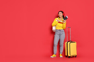 Happy traveller with passport and suitcase on red background. Space for text