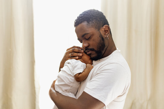 Caring black father with his newborn baby girl at home. Affection, baby. Rio de Janeiro, Brazil.