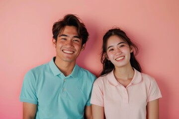 Fototapeta premium Portrait of a joyful asian couple in their 20s wearing a sporty polo shirt in front of pastel or soft colors background