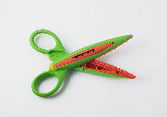 Green and orange craft scissor with corresponding pattern printed on its side for fast identification. Isolated on white.