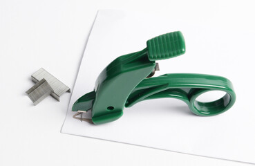 A plier-style staple remover, with some staples next to it, designed to easily remove staples from...