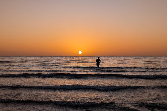 Distant silhouette of  a man standing in the sea at Sunrise, Costa Calma, Fuerteventura, Canary Islands, Spain