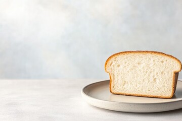 empty plate with single piece of bread placed on simple table in dim lighting conveying scarcity and need with plenty