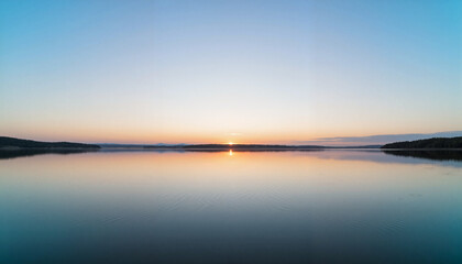 Fototapeta premium Serene sunrise over calm lake reflecting sky, nature's beauty