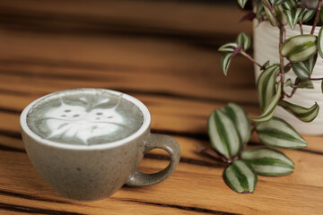 Cup of matcha latte with a butterfly drawing, prepared by a barista in a specialty cafe.