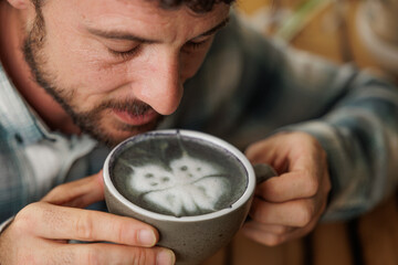 A young man enjoys a cup of specialty coffee with latte art to unwind from the work day. Copy...