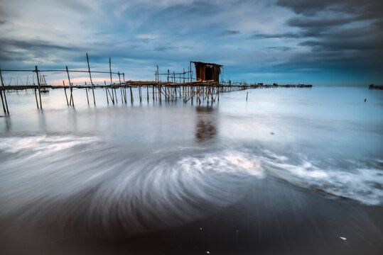 Receding water by a Bamboo pier on a beach at sunrise, Tanjung Kait, Mauk District, Tangerang Regency, Banten, West Java, Indonesia