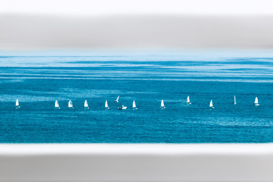 View through a fence of a Row of sailboats sailing in sea, St Paul's Bay, Malta