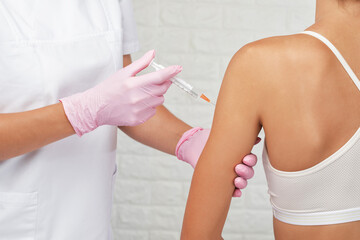 Young woman getting injection against coronavirus at hospital. Healthy lifestyle concept.